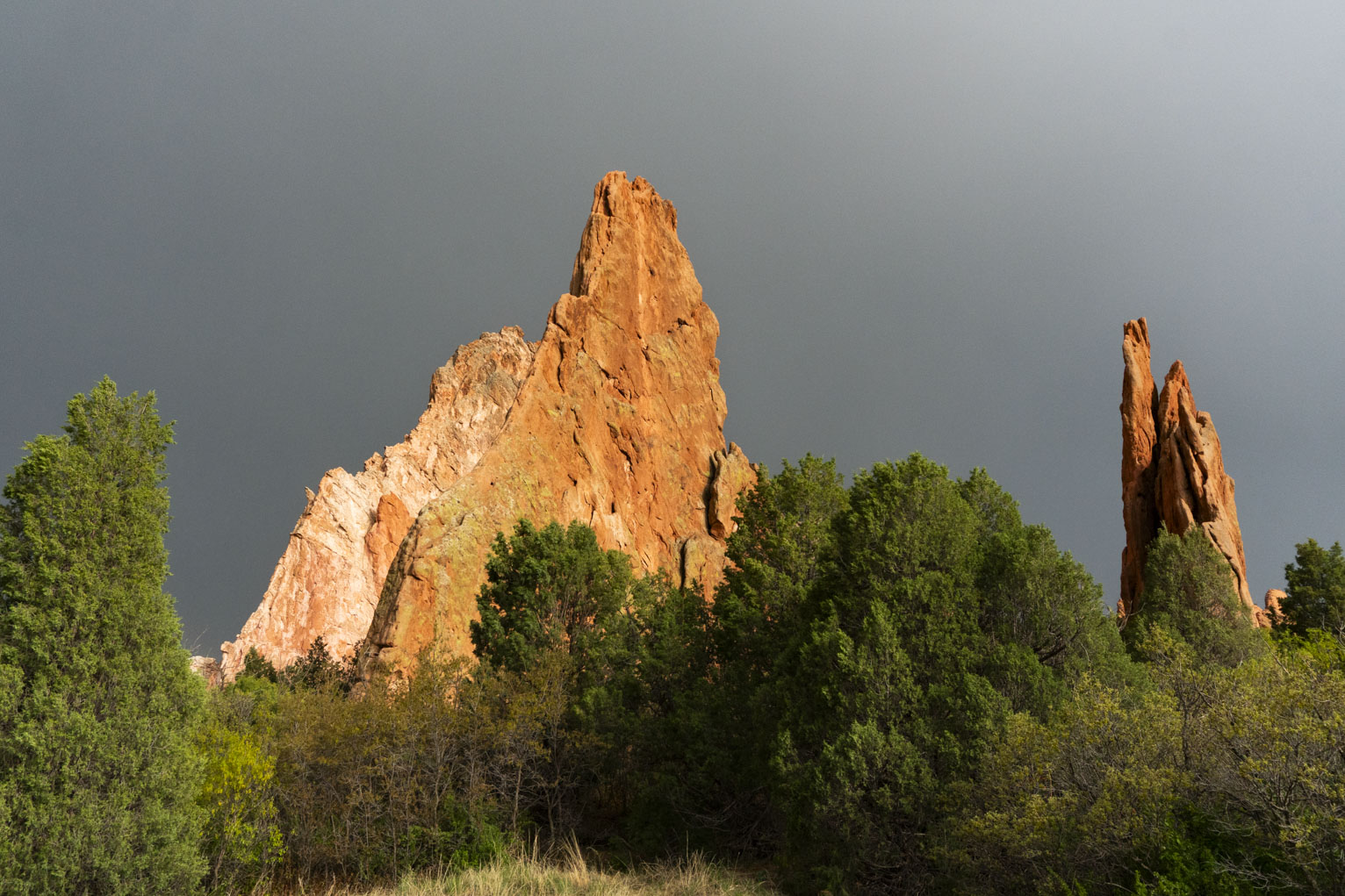 Two huge red rock formations poking out of the trees nearby